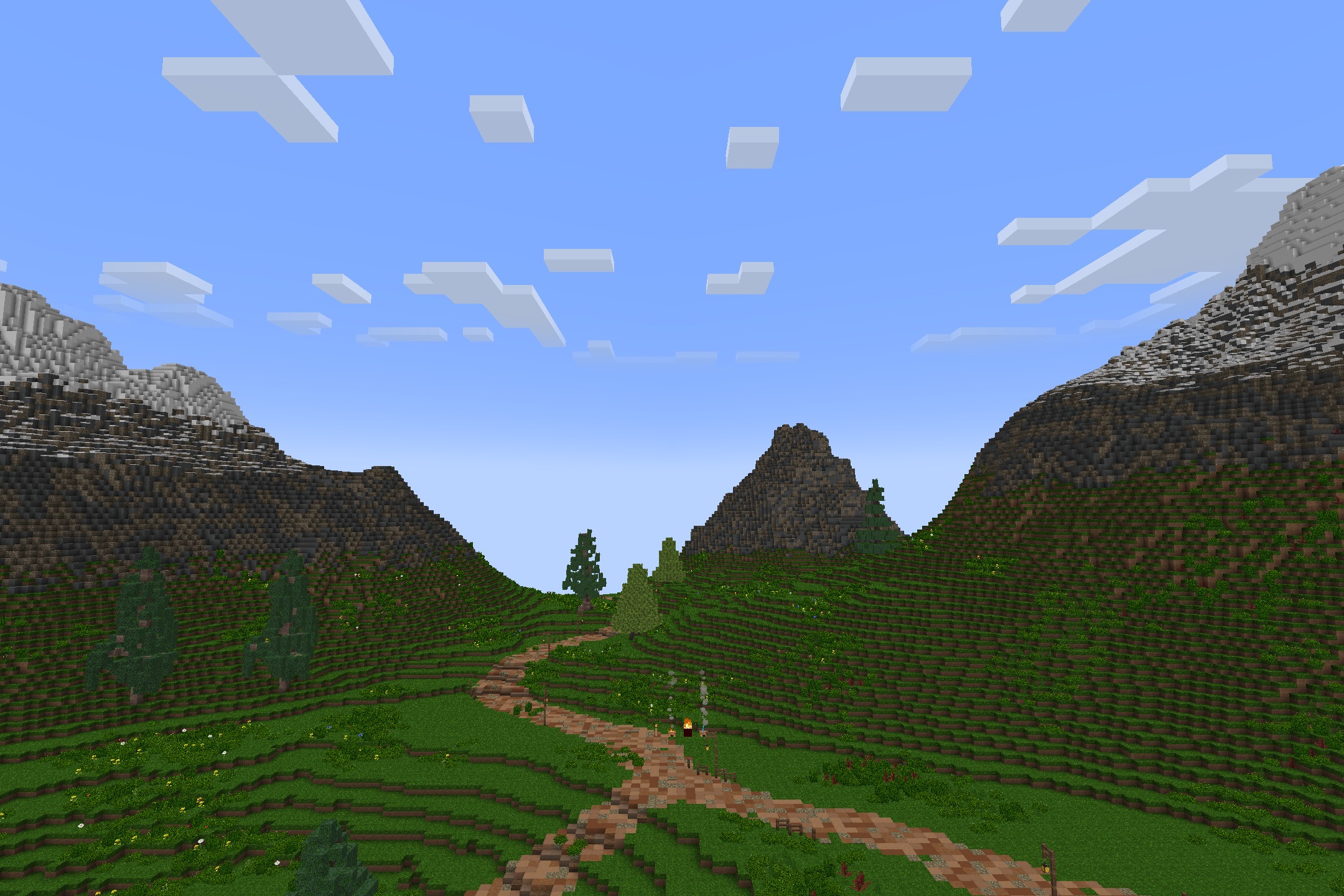 A winding dirt path leads through green hills toward distant mountains