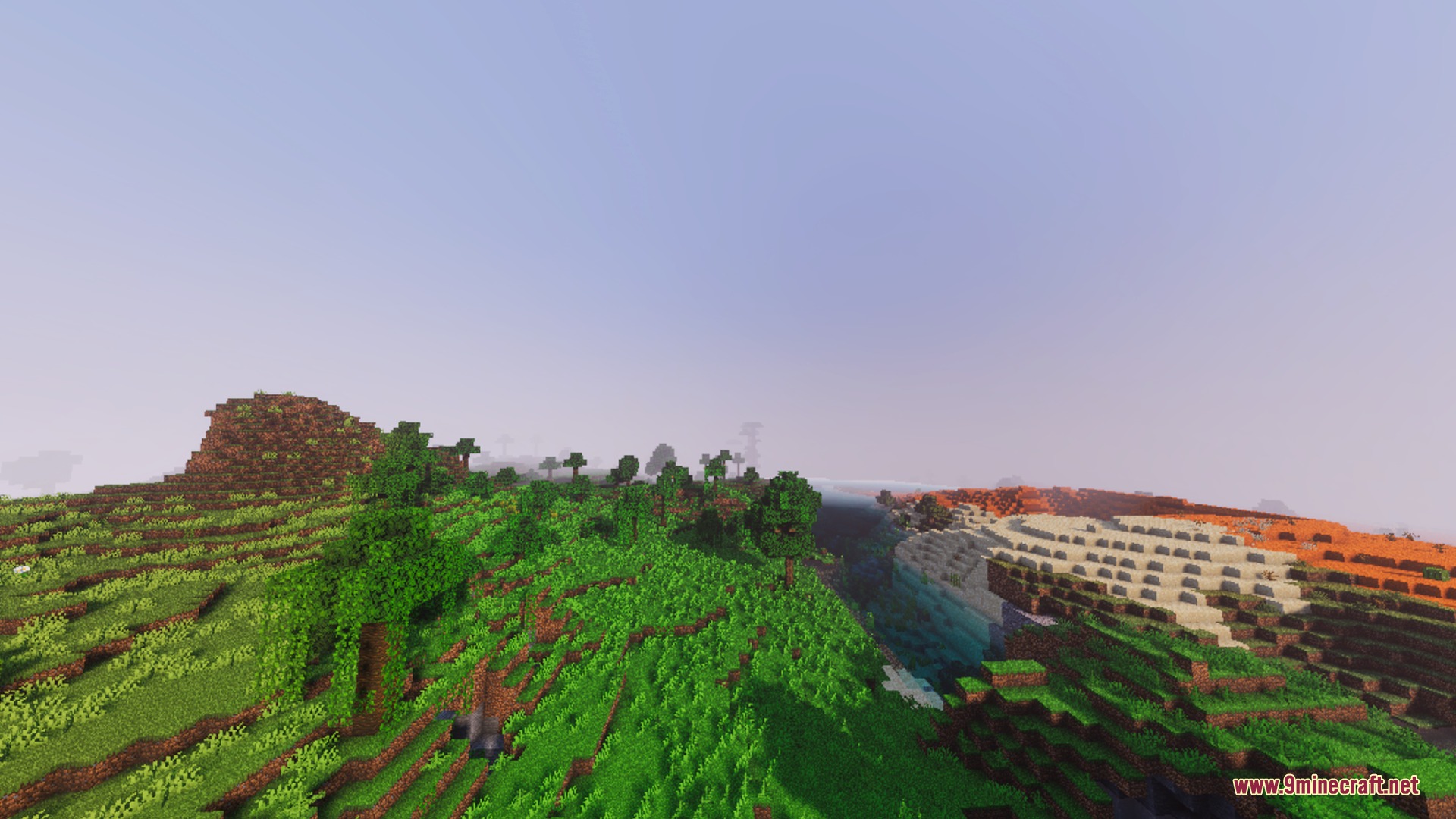 Lush green hills and a deep canyon under a warm hazy sunset sky