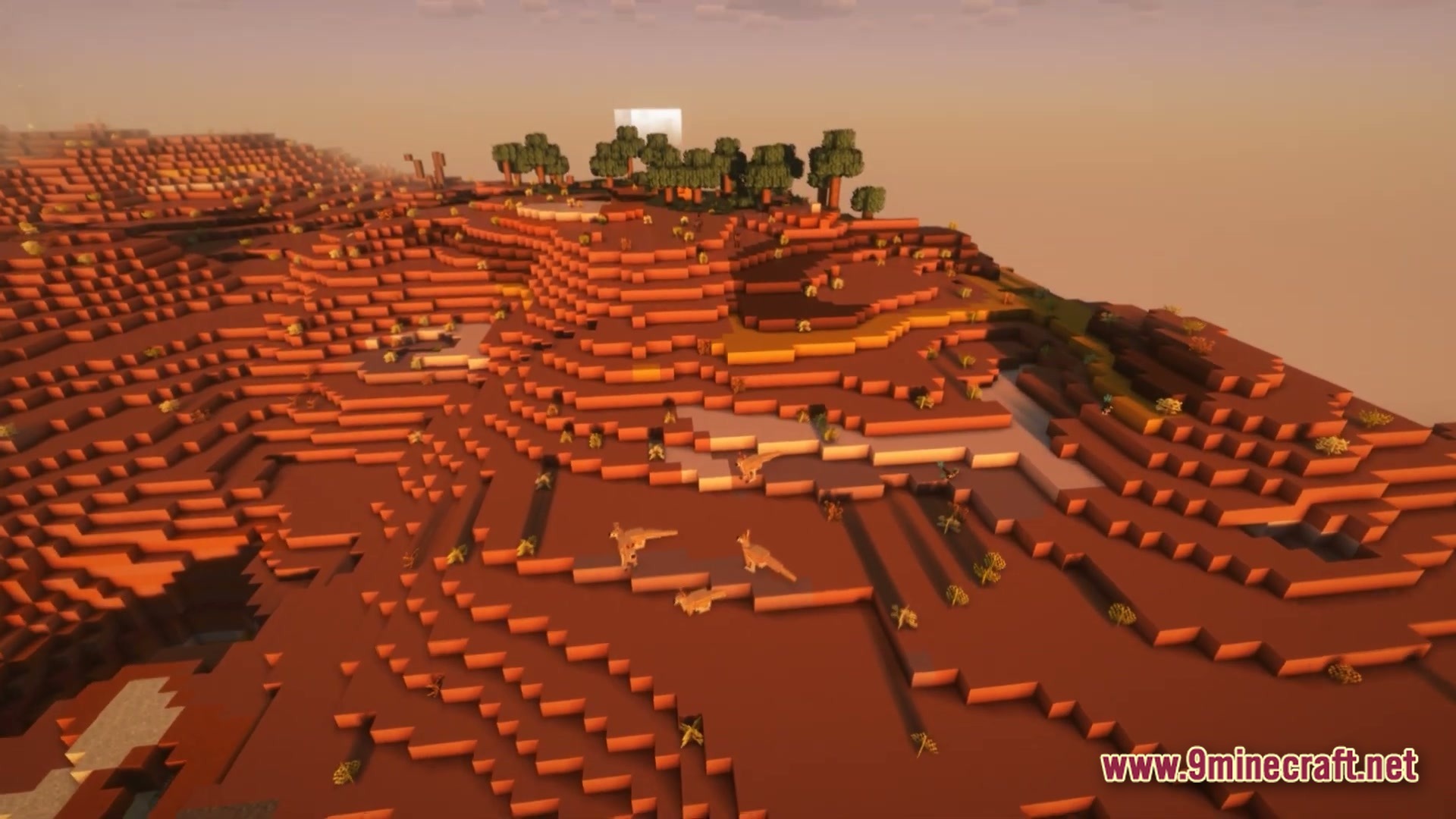 Vivid Kinetic Ether Modpack Screenshot 5 A group of dinosaurs wanders across a red desert mesa biome during a hazy sunset