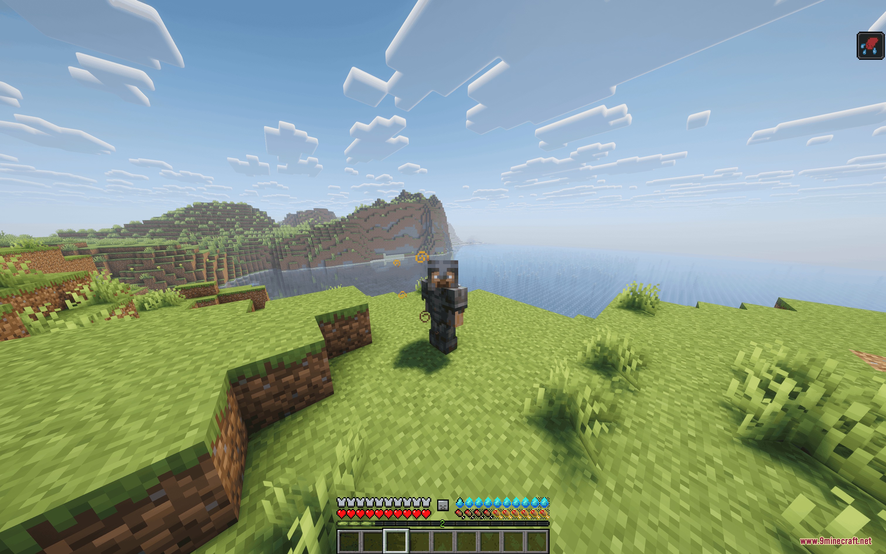 A player in netherite armor stands on a hill with thirst bar
