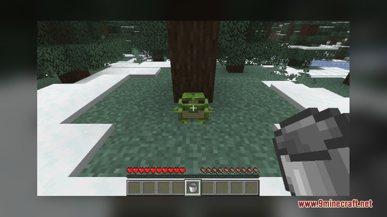 Bucket of Frog Mod Screenshot 1 Player aims a bucket at a green frog in a snowy forest biome