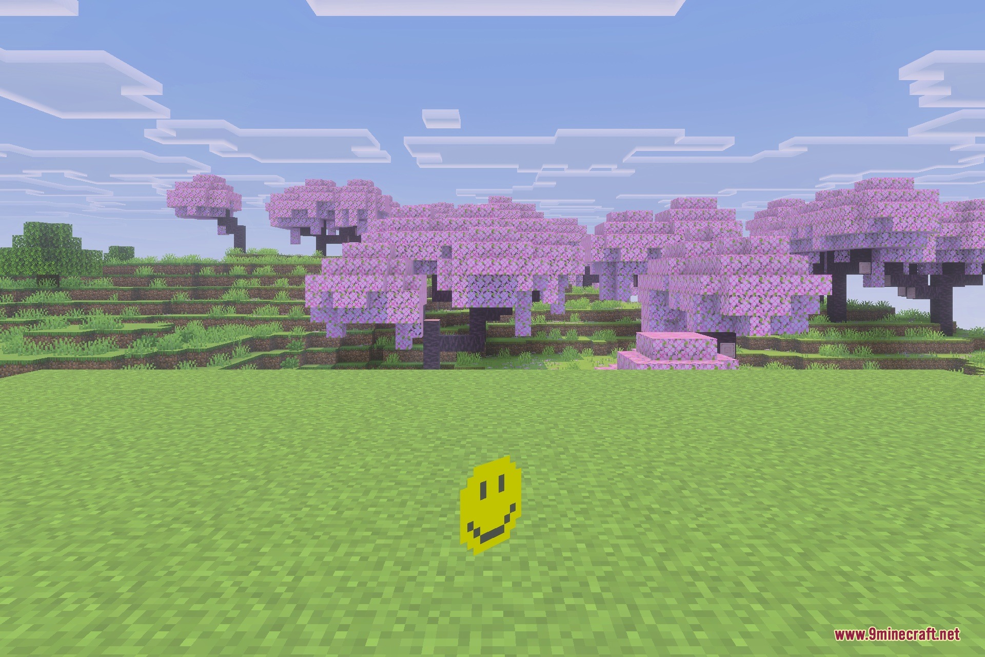 A happy yellow Verity entity stands in a field near cherry blossom trees