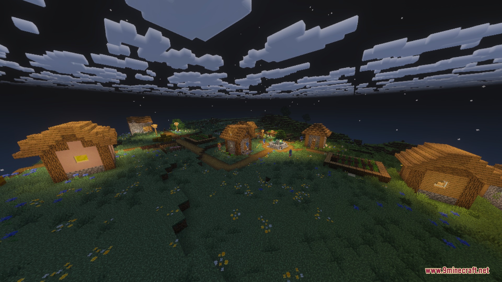 Dark night sky with blocky white clouds over a peaceful illuminated village