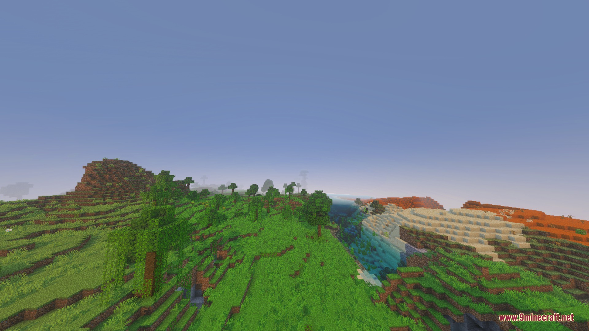 Vibrant green hills and a sandy shore under a clear blue sky