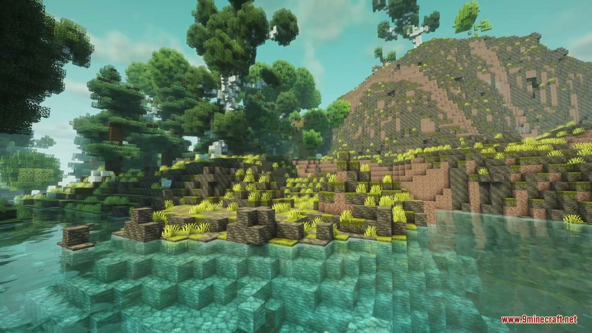 Clear turquoise water flows past a rocky Maquis shrubland hill with trees