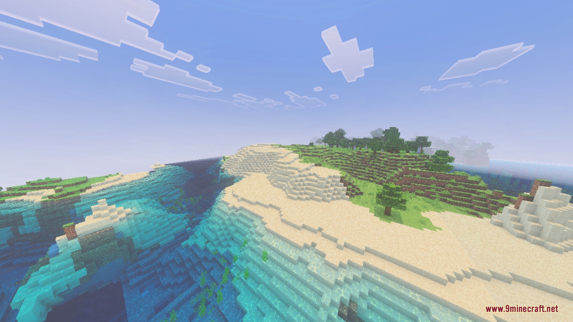 Crystal clear water flows along a white sandy beach with green hills nearby