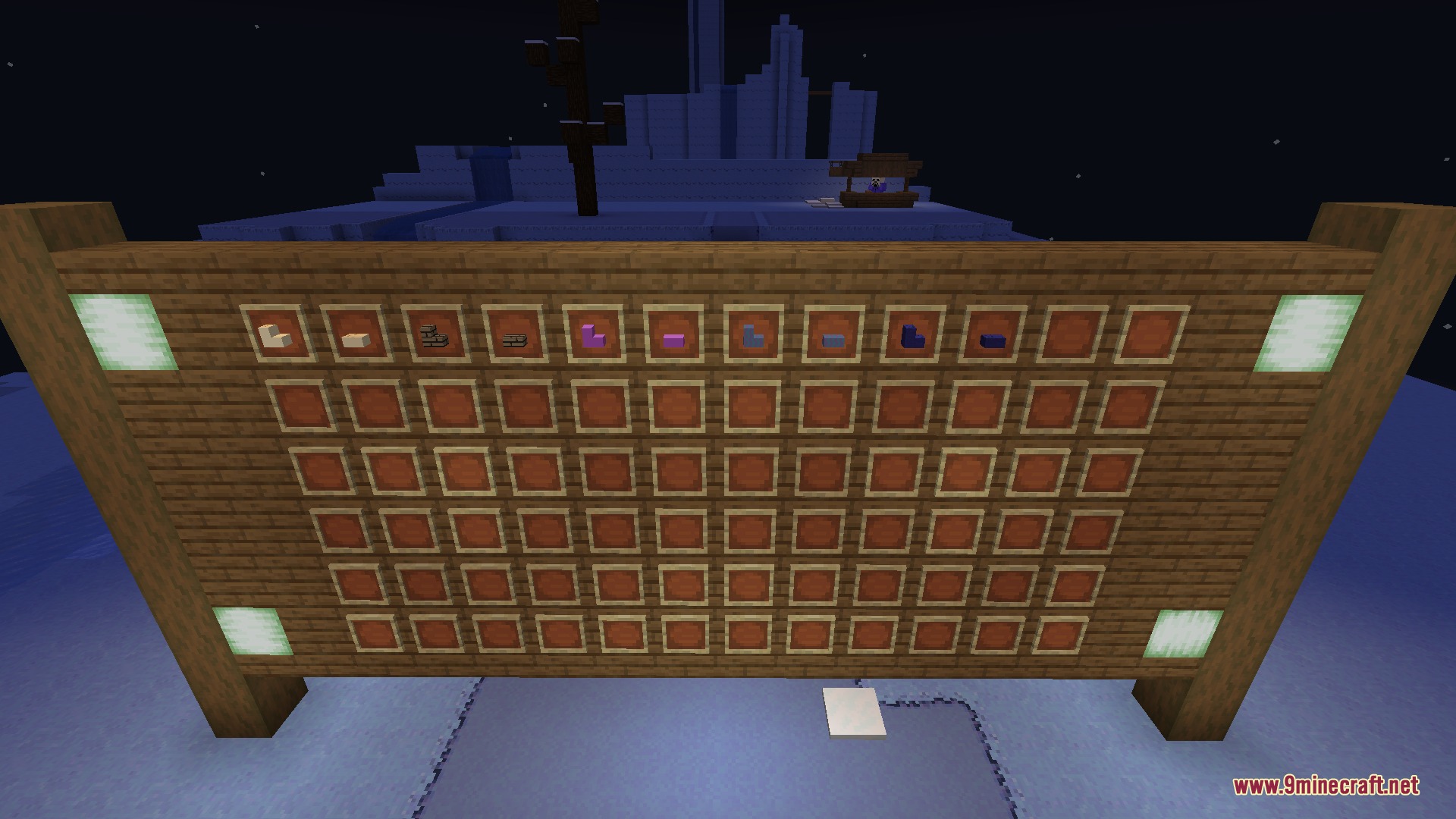 A wooden wall displaying various colorful building blocks in item frames at night