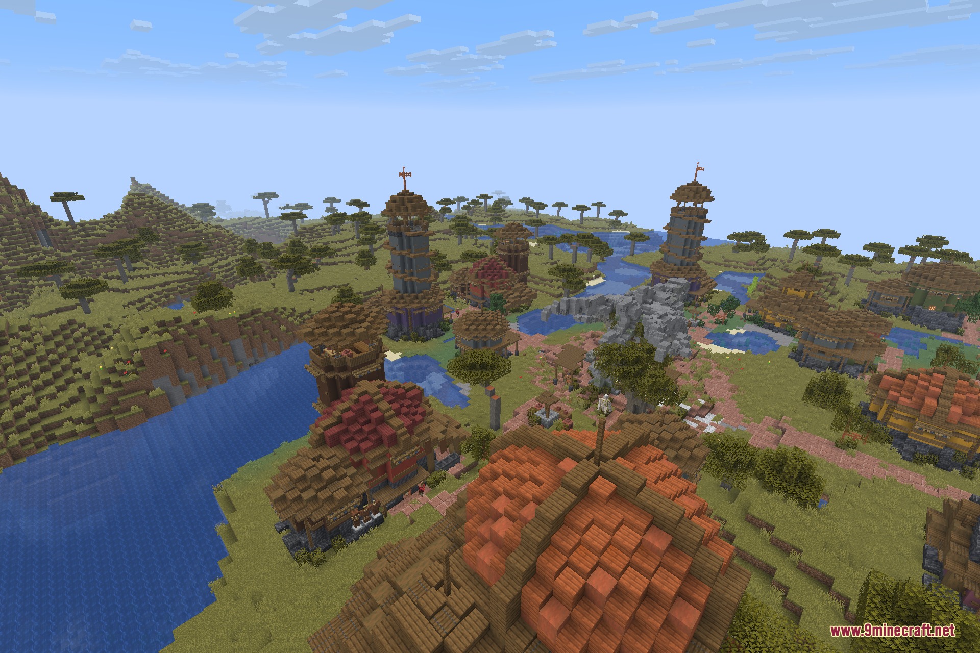 A large savanna village with tall towers and houses near a river