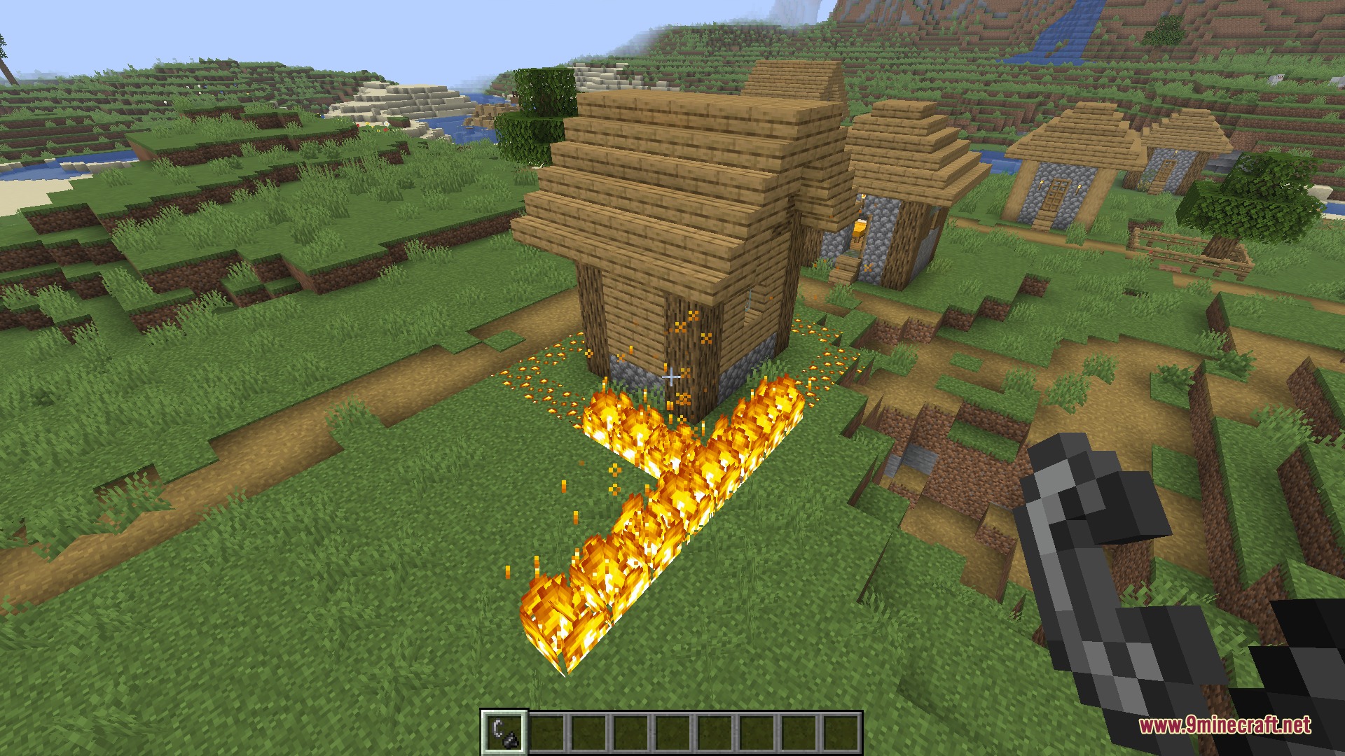 Infernal Curiosities Mod Screenshot 3 A player creates a line of blaze fire near a wooden village house