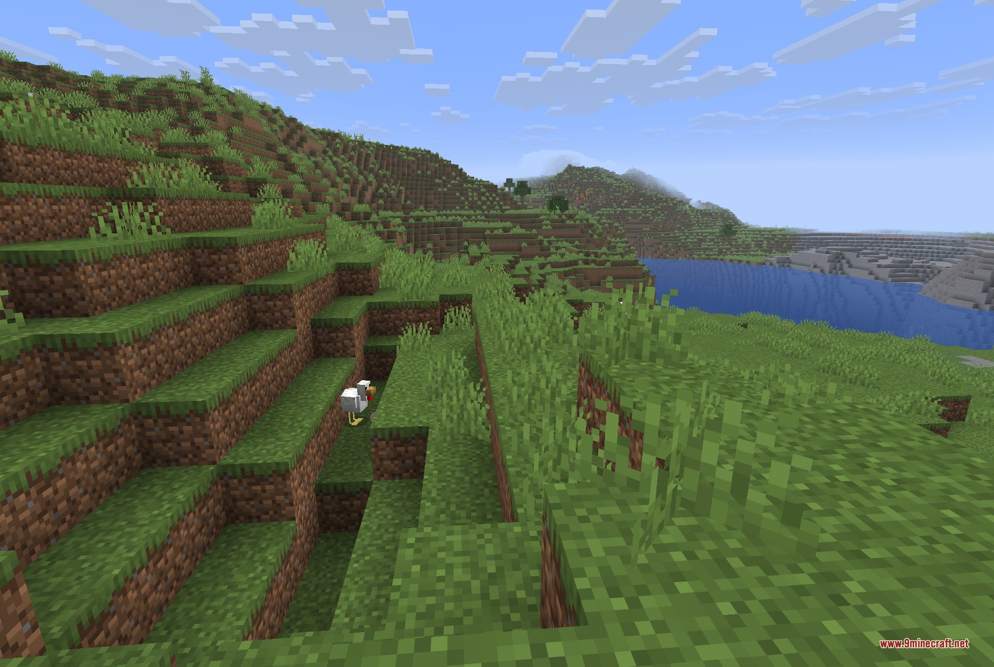 JackFredLib 9minecraft Mod Screenshot 3 A white chicken stands on a grassy hillside overlooking a blue lake