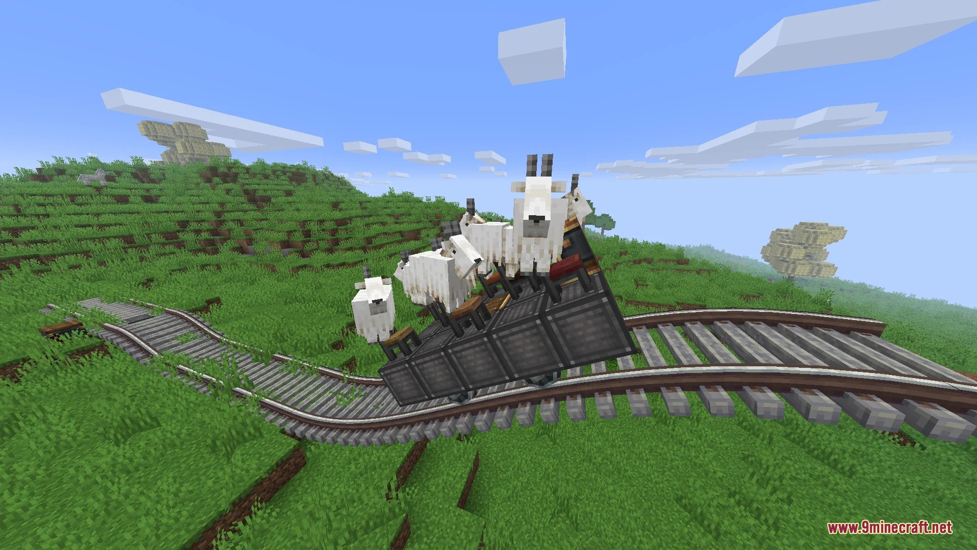 White goats sitting on chairs on a moving train contraption along curved tracks