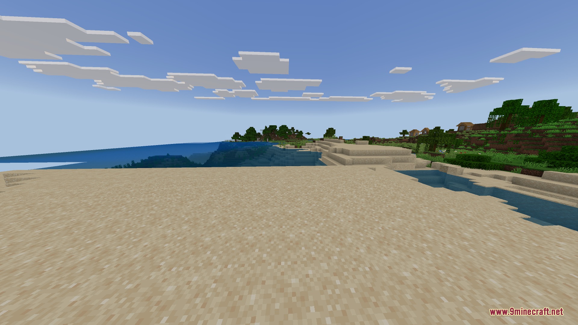 A wide sandy beach overlooking the ocean with a village nearby