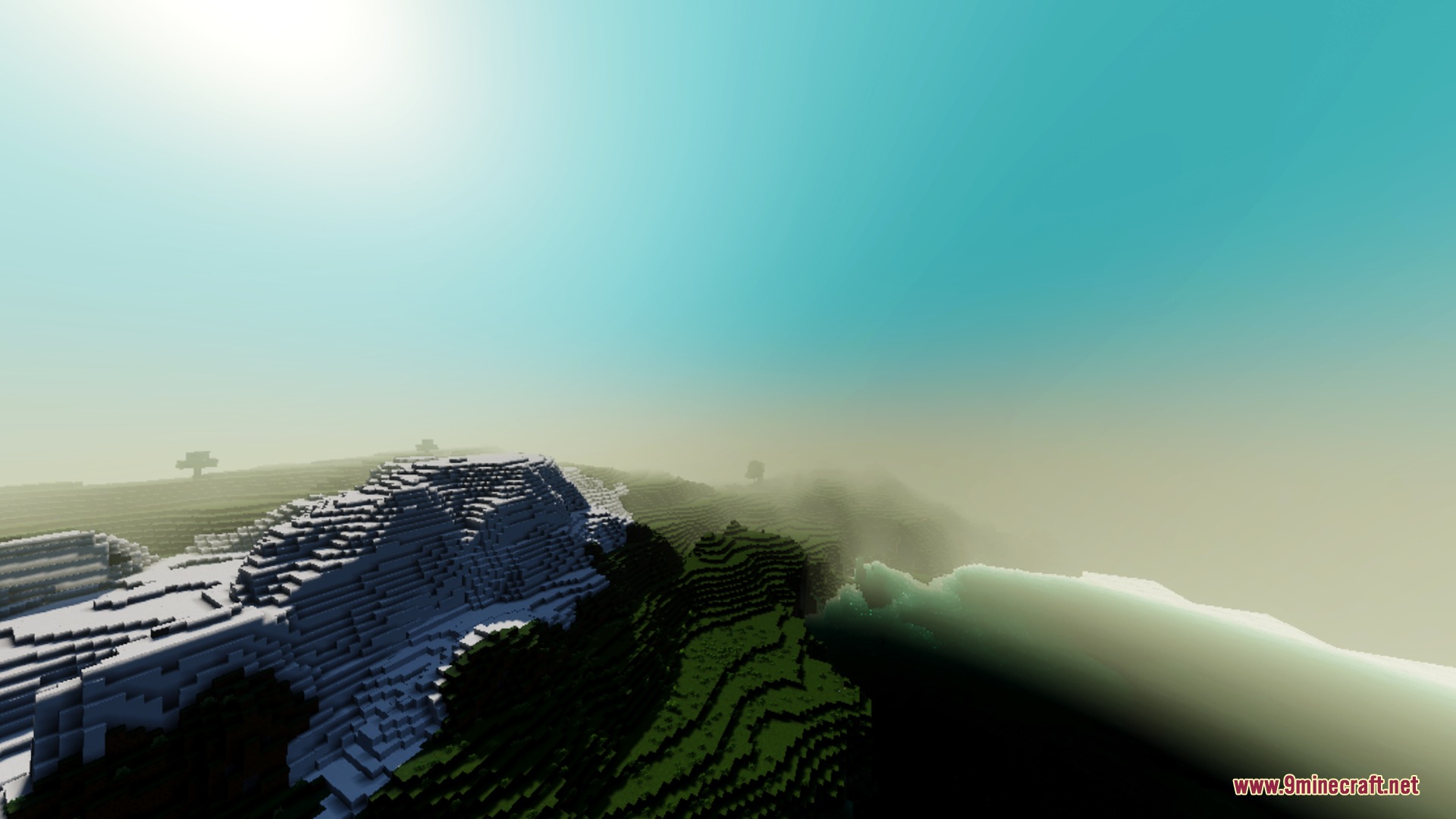 Vibrant sunlight creates a hazy glow over snowy mountains and green hills