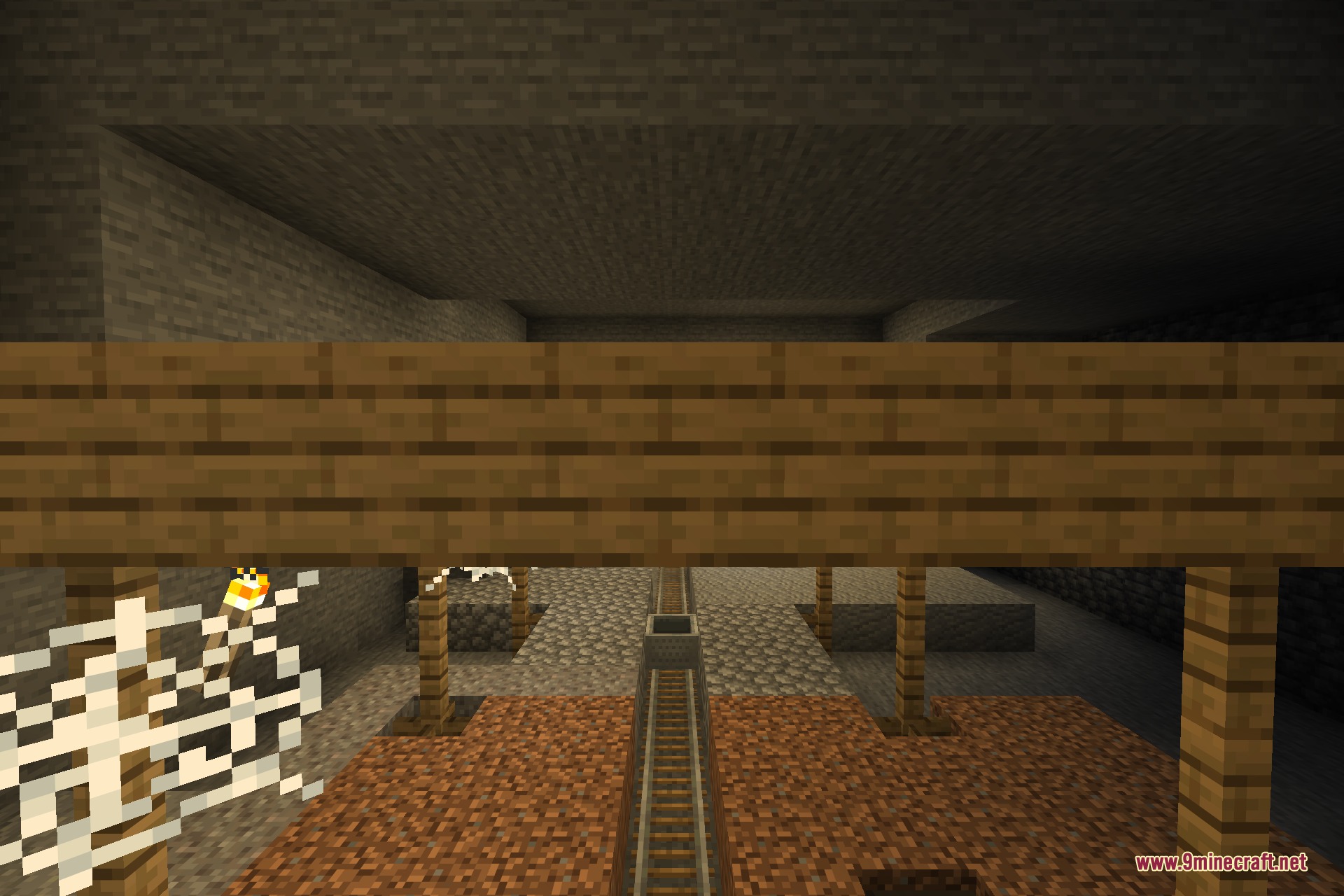 An abandoned mineshaft corridor with rails, beams and cobwebs