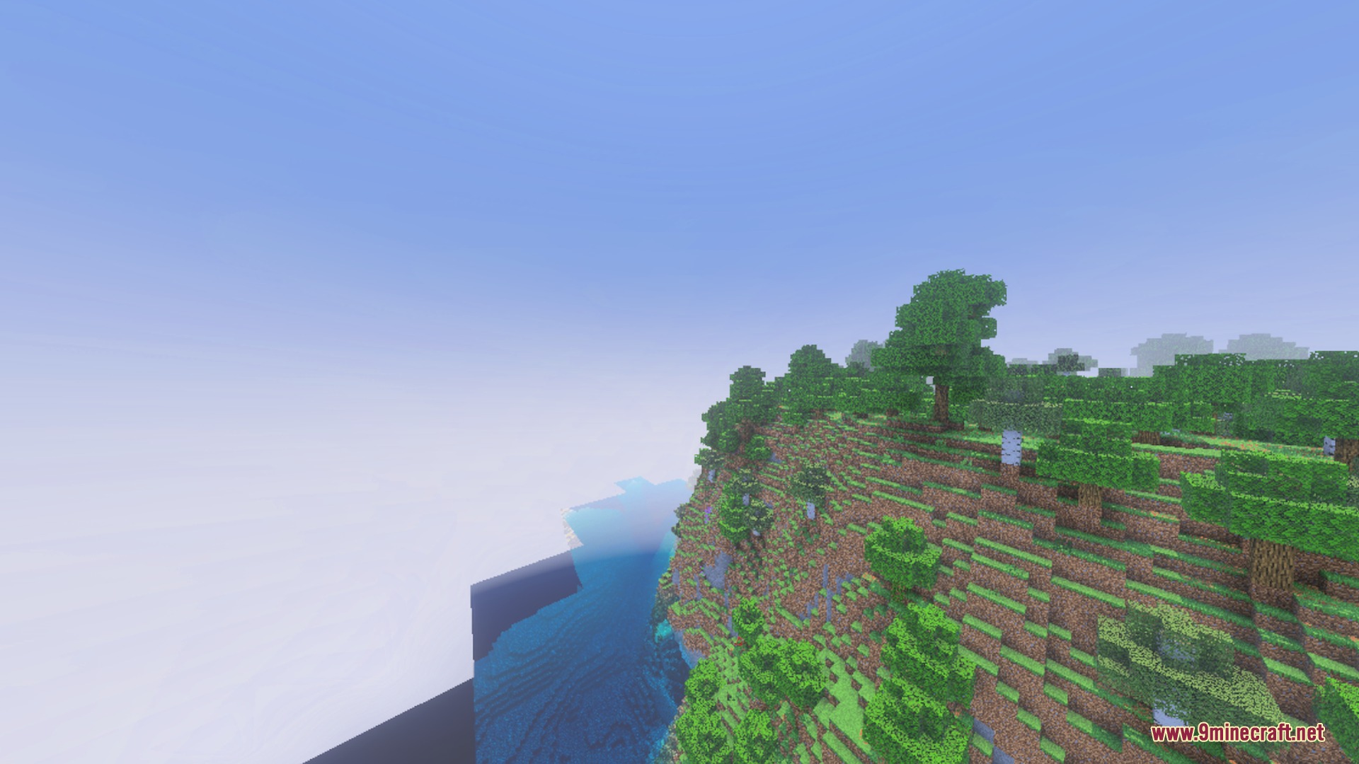 A steep cliffside with lush trees overlooking a vast body of water