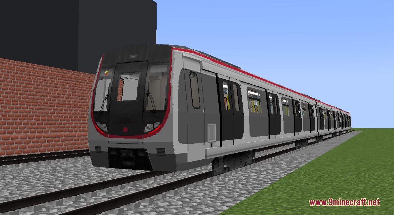 A long grey and red metro train on a gravel railway track
