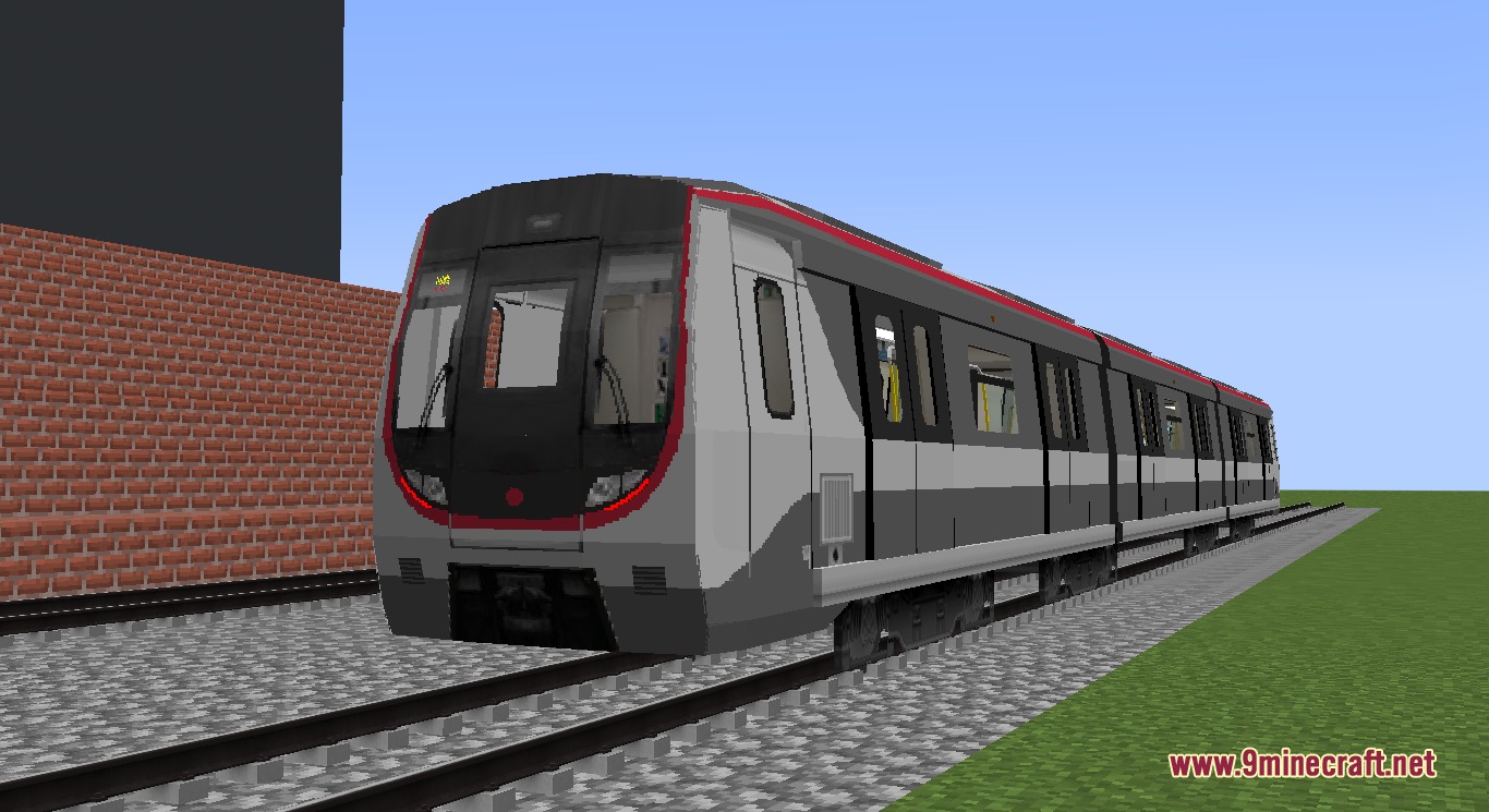 A long grey and red metro train on a gravel track