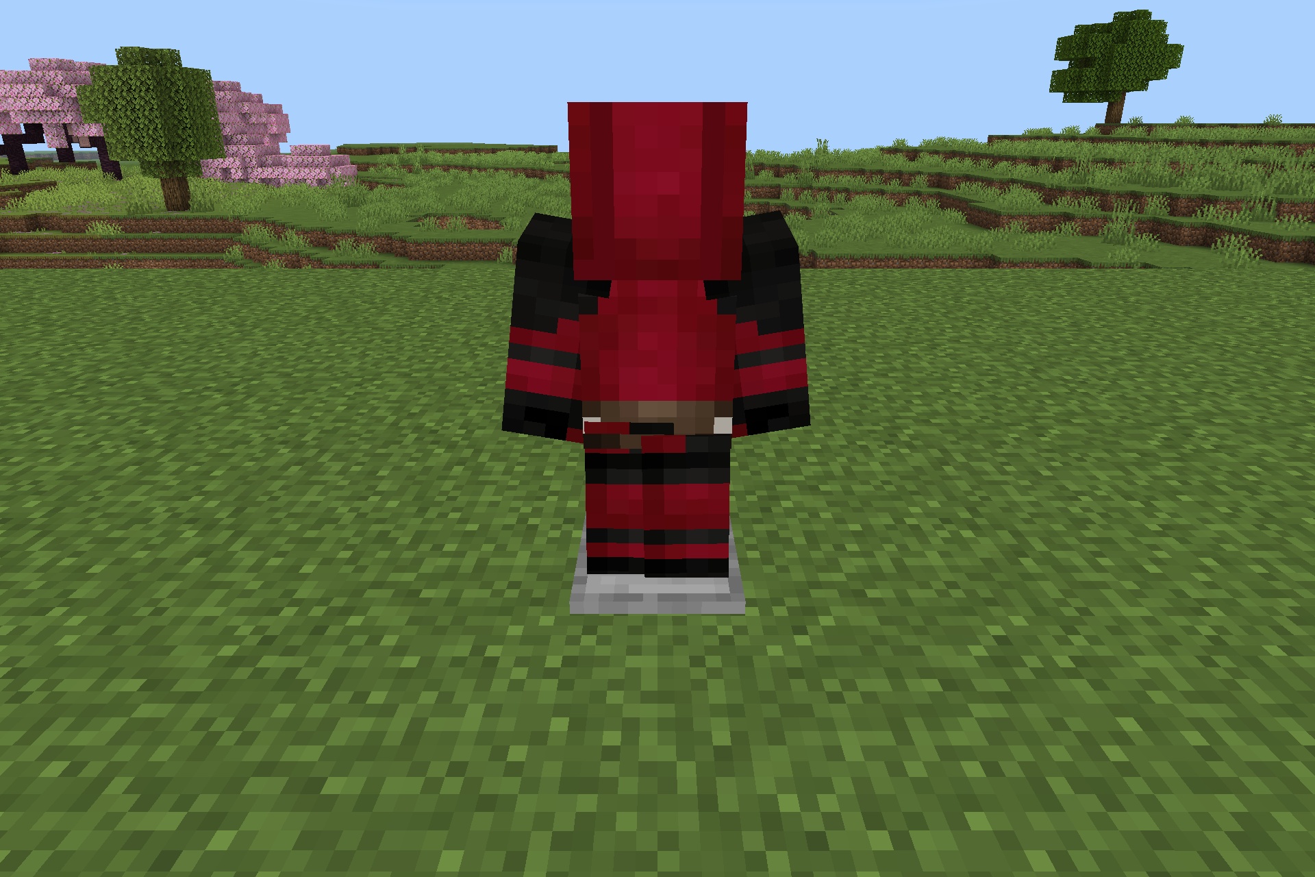A red and black superhero suit displayed on an armor stand outdoors