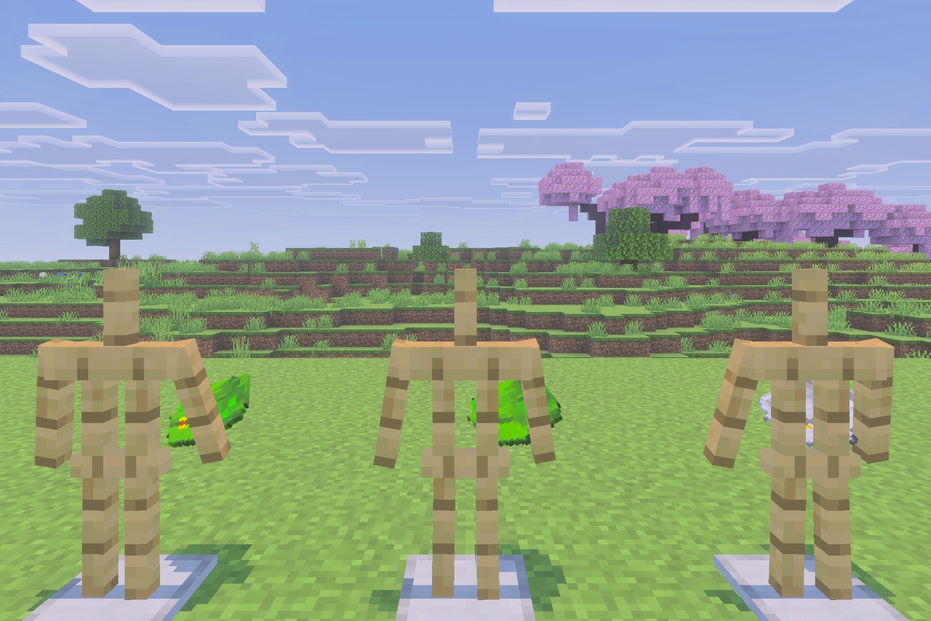 Three armor stands showcasing various backpack designs in a wide grassy field