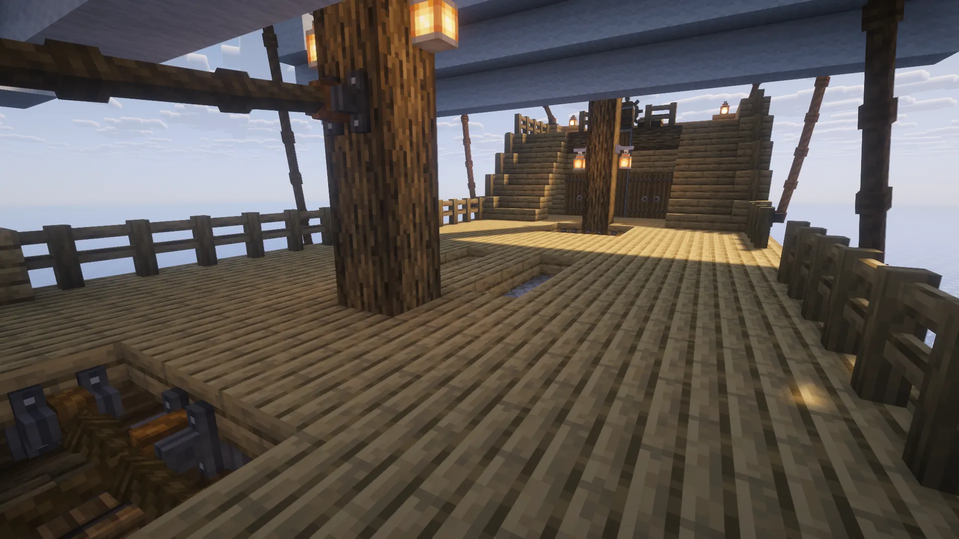 The wooden deck of a ship featuring masts and hanging lanterns
