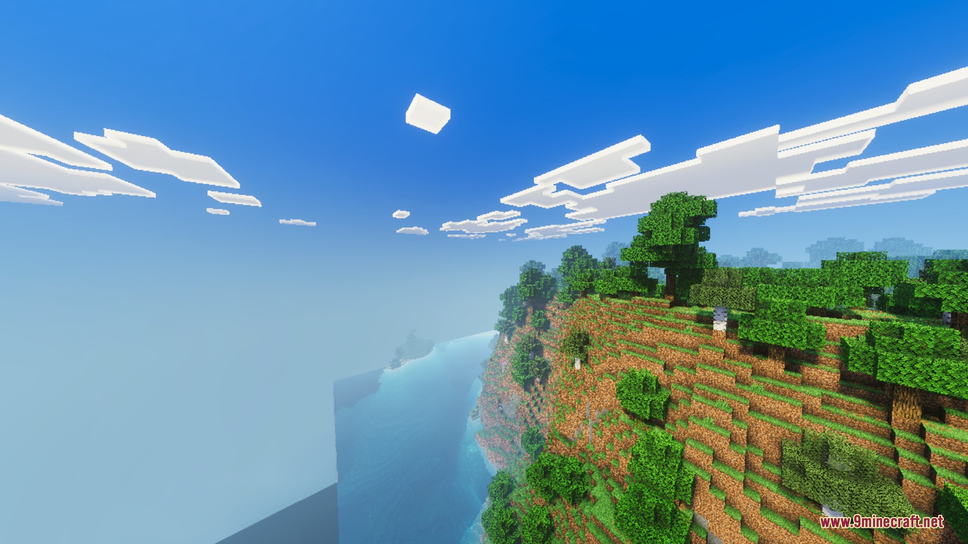Warm sunlight illuminates a steep cliff overlooking a vast blue ocean
