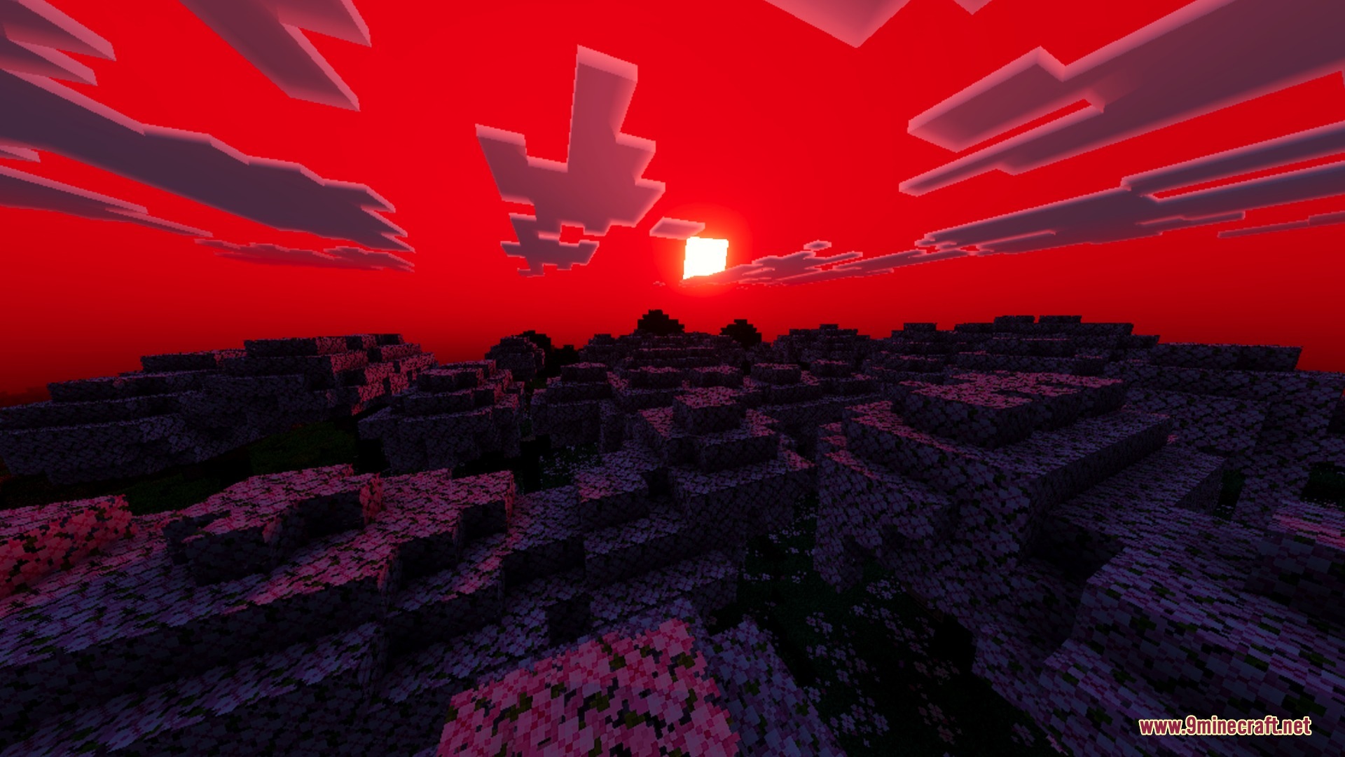 The sun shines through a deep red sky over a dark blocky landscape