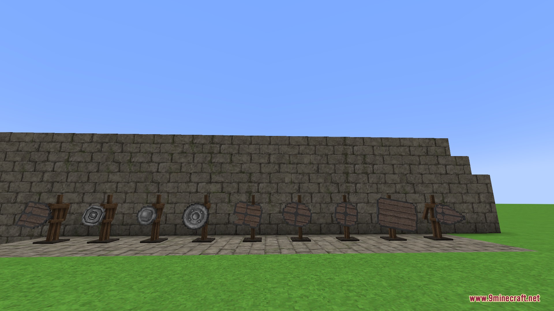 Various medieval shields displayed on wooden stands against a stone wall