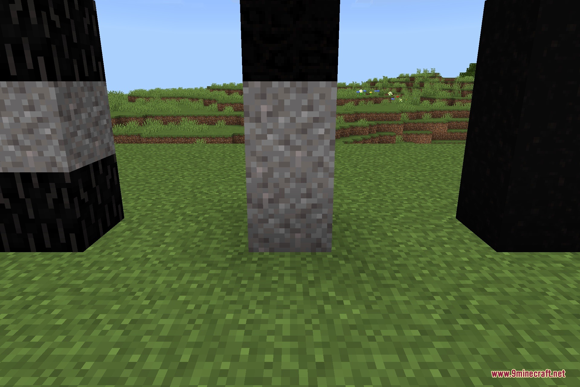 Dark corrupted blocks and stone pillars placed on a grassy field in Minecraft