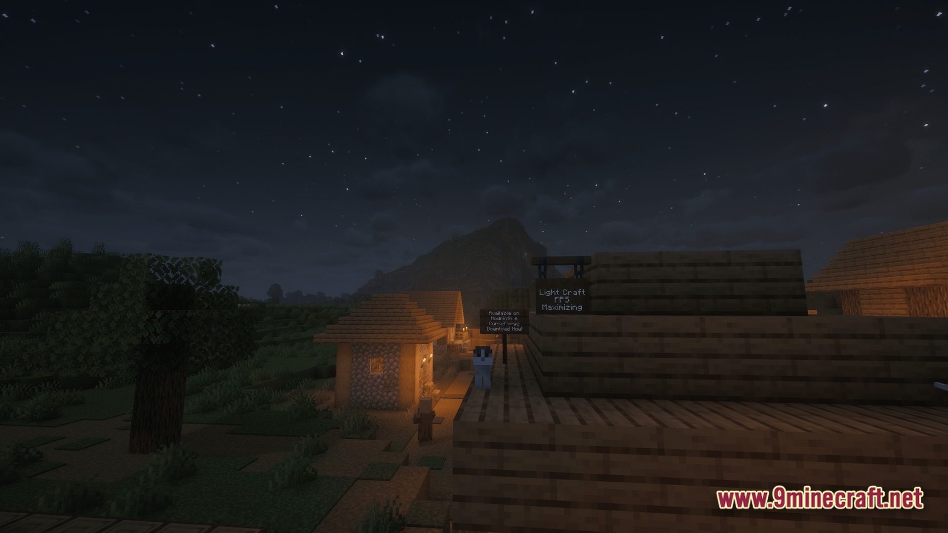 A small village at night with a mountain in the background under a starry sky