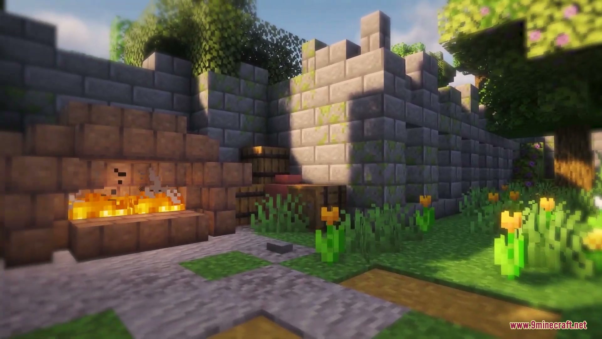 A stone fireplace burning next to a stone wall with barrels and flowers