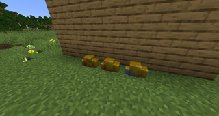 Three gold piles on grass next to wall