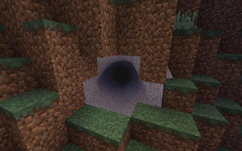 A dark, mysterious cave entrance in a hillside.